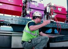 An APS Upgrade contractor directs a forklift operator as he gently lowers one of the APS Upgrade modules off of a truck.